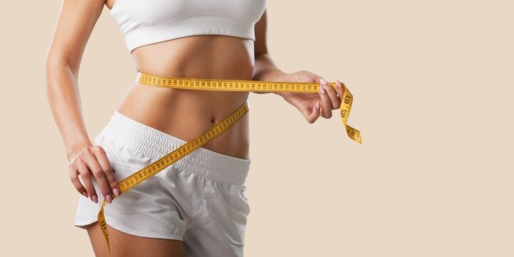 Beautiful fit sporty girl in underwear with measuring tape at hips. Perfect woman body concept.