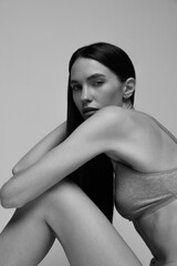 Fototapeta premium Black and white portrait of beautiful young woman attentively looking at camera, posing in underwear