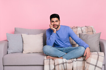 Photo of cute funny arabian man wear long sleeve shirt sitting sofa arm chin empty space isolated pink color background