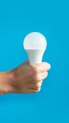 hand holds led lamp. idea. New idea or inspiration concept. Startup concept. blue background. Vertical image.