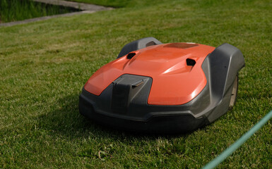 Robotic Lawn Mower on green grass background.Automatic robot lawnmower in modern garden.Green grass...