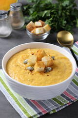 Homemade pumpkin cream soup with chicken and white bread croutons in bowl on gray background