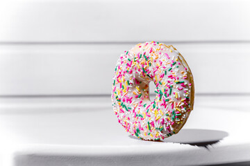 Sweet donut with white frosting and sprinkling