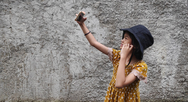 Image of Asian child posing selfie with cellphone on natural background