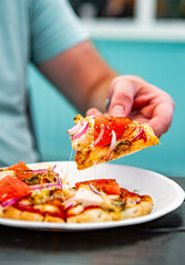 man Hand takes a slice of pita Pizza with Mozzarella cheese, ham, bacon, tomato, Spices in outdoor...