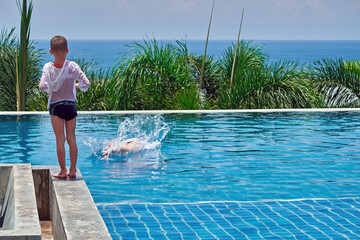 Two boys playing and swimming in the outdoor pool, copy space.