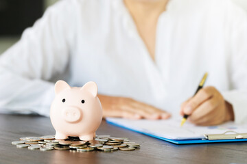 pig piggy bank on the table and woman calculating financial accounts for save money, saving money or savings concept.