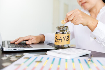 Pile of coins in a bottle on the table and woman picking up a coin for save money, saving money or savings concept.