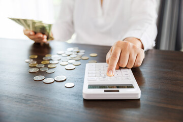 woman calculating financial accounts and holding dollar bill for save money, saving money or savings concept.