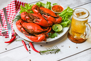 seafood plate with herbs spices rosemary lemon lime salad lettuce vegetable, fresh crab on white plate seafood sauce and mug beer glass, crab cooking food boiled or steamed crab red in the restaurant