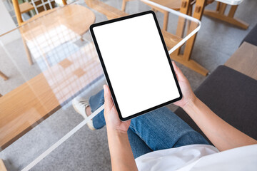 Mockup image of a woman holding digital tablet with blank white desktop screen in cafe