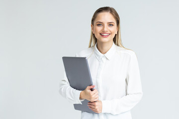 Portrait of a smiling businesswoman carrying laptop while standing isolated over white background