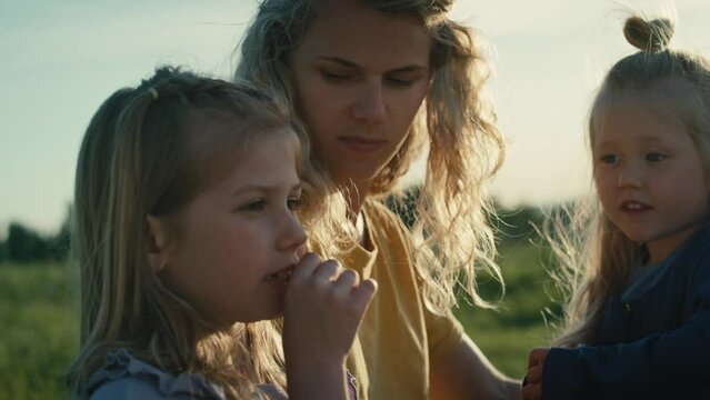 Mom with two little daughters talking together at the meadow. Shot with RED helium camera in 4K.   