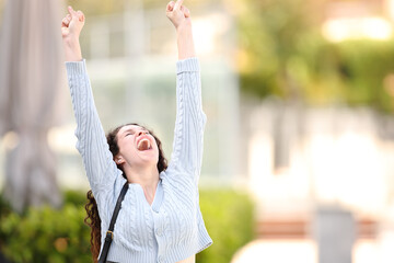 Excited woman raising arms celebrating in the street