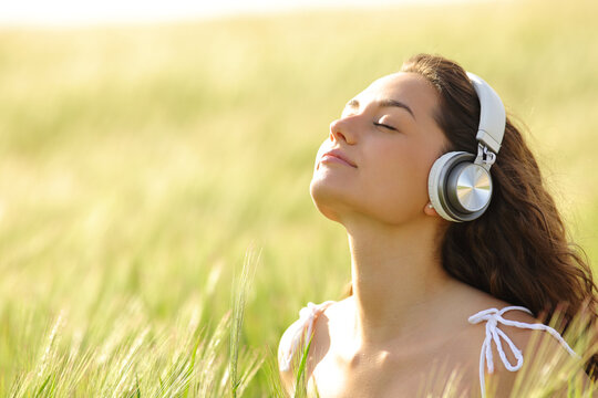 Woman with headphones meditating in a wheat field