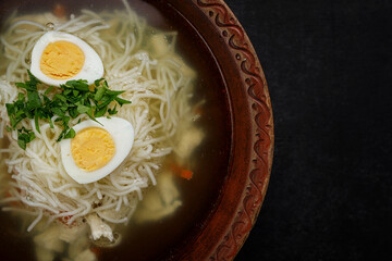 Chicken broth, with noodles, herbs and egg, studio light