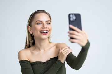 Portrait of a smiling woman taking selfie with mobile phone isolated over white background