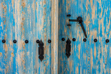 A part of old worn looking blue painted door with black wrought iron latch and handle close up image as background. 