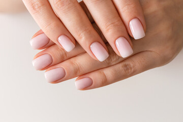 Female hands with beautiful nails with stylish trendy nude manicure.