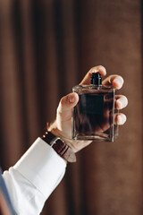 Perfume or cologne bottle and perfumery, cosmetics, scent cologne bottle, male holding cologne. Masculine perfume, man in a suit. Male holding up bottle of perfume. Man perfume, fragrance.