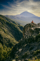 man sitting on a rock El Teide volcano at sunset in background Tenerife  Canary islands
