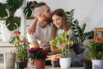 Girl and her father are planting flowers together at their home.