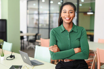 Successful young african-american female entrepreneur, small business owner, female office employee, black businesswoman wearing green casual shirt stands in confident pose with arms crossed - Powered by Adobe