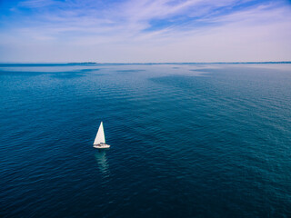 Yacht sailing on opened sea. Aerial view of sailing boat on sea surface.
