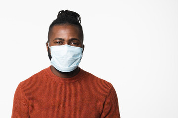Pandemic illness concept. African-american young man wearing protective face mask against coronavirus covid19 looking at camera isolated in white background.