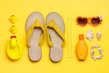 Swimming accessories - trendy beach flip flop, duck toy, orange sunblock, heart - shaped glasses, shell bracelet on yellow background Flat lay Top view Summer, travel, vacation concept