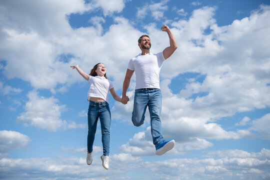 carefree father and daughter jump in sky