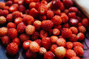 a lot of wild strawberries on a clay saucer, top view of forest red berries on a plate, wood style, farming
