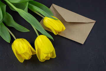 Yellow tulip near blank greeting card and envelopes on black background