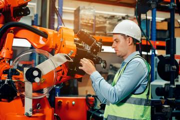 Male engineer checking and inspection control a robot arm machine welding steel in an industrial factory, Fast and highly secure.