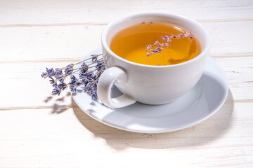 Organic lavender tea cup. Hot floral herbal tea with fresh lavender flowers, in white ceramic cup on wooden background copy space