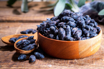 Bowl with fresh  raw farm haskap berry, garden grown honeysuckle, honeyberry, on wooden background copy space