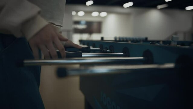 Girl hands grasping table football rods close up. Schoolgirl enjoy soccer match.