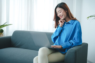 Obraz premium girl sitting on the sofa at home working on the computer. beautiful smile