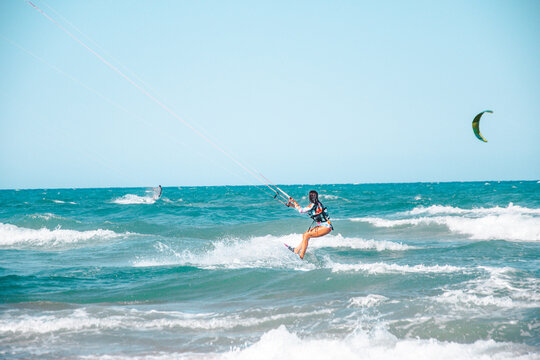 Joven surfera disfrutando haciendo kite surf en la playa. 