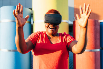 Happy woman wearing virtual reality simulator gesturing on sunny day