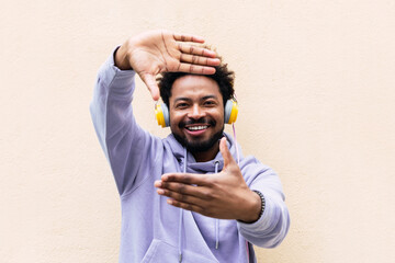 Smiling man making finger frame in front of cream colored wall