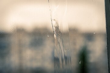 A jet of water on a dirty window pane. Blurred and unfocused background. Selective focus.