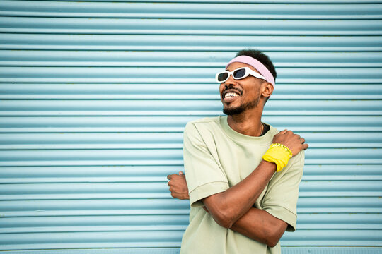 Happy man wearing eyeglasses and headband in front of blue shutter
