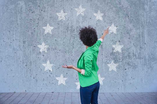 Woman pointing at European stars painted on wall
