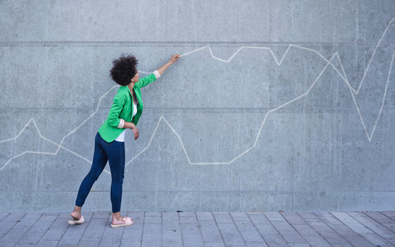 Young Woman Pointing At Chart Painted On Wall