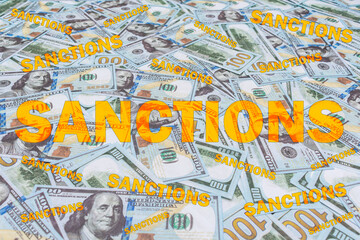 The word Sanctions on the background of many hundred dollar bills. The concept of financial restrictions and prohibitions