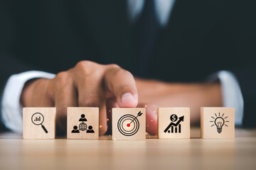 Businessman Hand pushing target board icon on wooden cube block in front of icon business strategy and Action plan Service concept of business to success Business strategy planning To market victory.