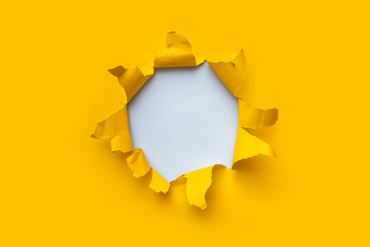 Torn hole in yellow paper with white empty background. Copy space, mockup. Place for text or logo.