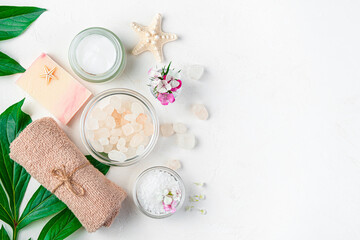 A gentle spa composition with organic cosmetics on green leaves on a light background. View from above. copy space