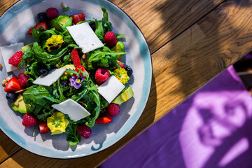 Salad with arugula, raspberries, strawberries, avocado